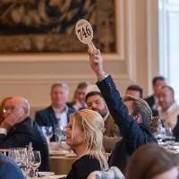 A man with a raised auction paddle bidding in The Distillers One of One Auction in 2023