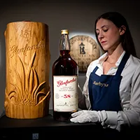 A Sotheby's staff member showing one of the auction lots at The Distillers One of One Preview Exhibition in 2025